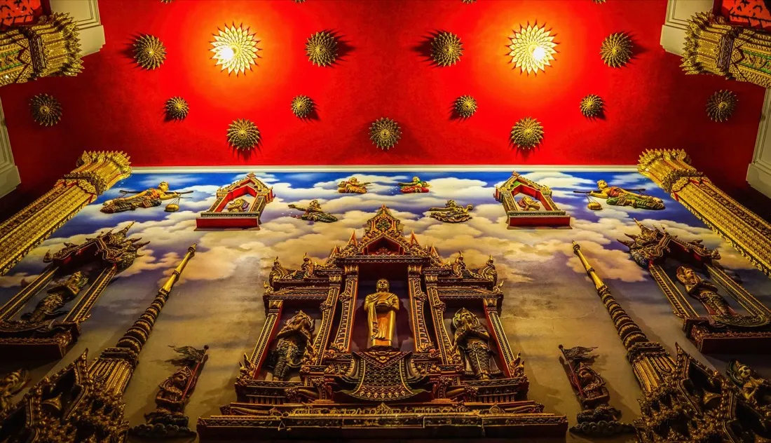 A red-and-gold shrine wall with golden medallions and a central Buddha figure